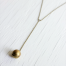 Vintage ball locket strung on a brass chain laying on top of a wood board background