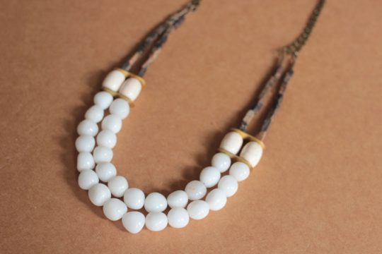 White beaded necklace with 2 layers laying on a brown background