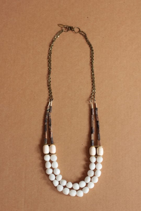 Necklace with two strands of white agate beads layered laying on top of a brown background