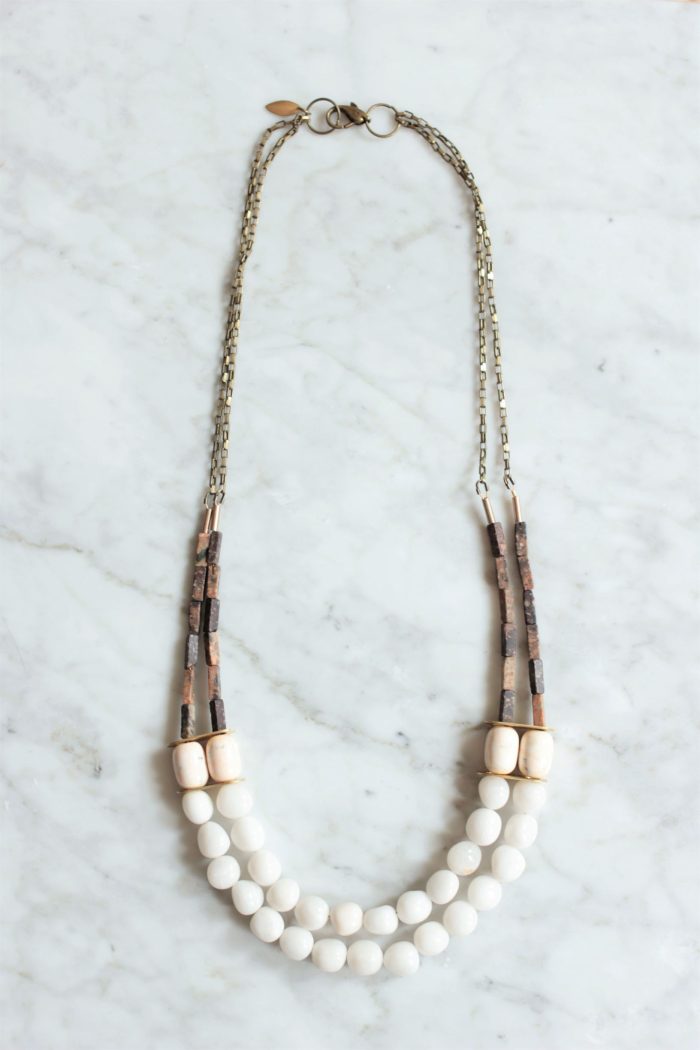 White stone statement necklace with 2 multi strand layers laying on top of white marble table